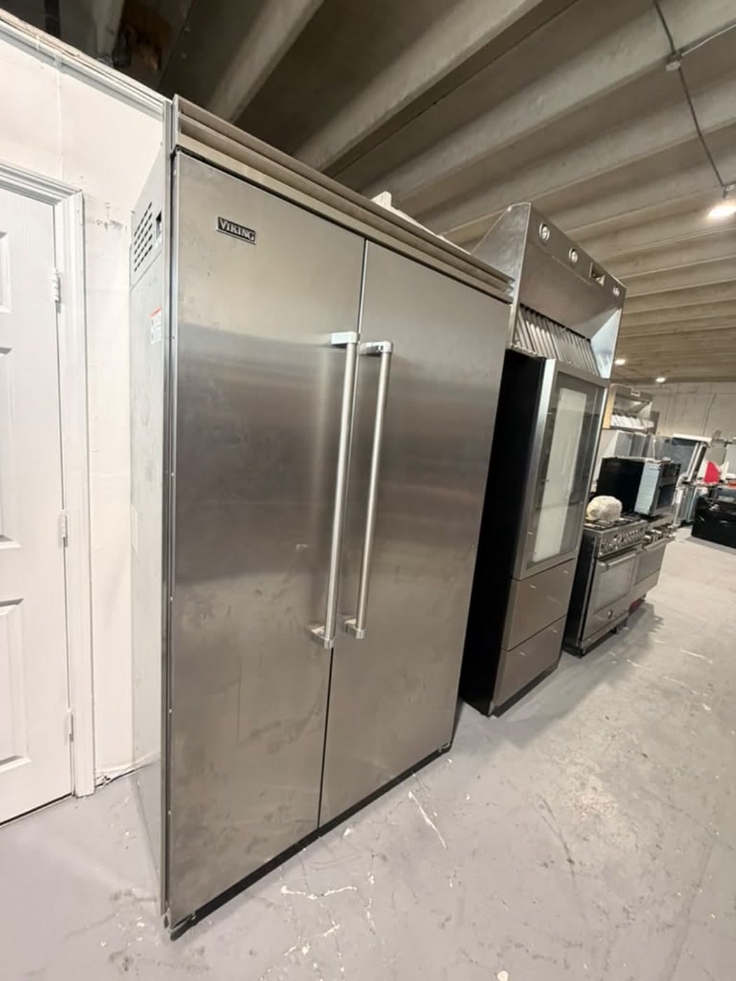 Actual viking 48-inch side-by-side refrigerator photographed in Oakland Park — angled exterior view showing the lower-left toe-kick and foot area
