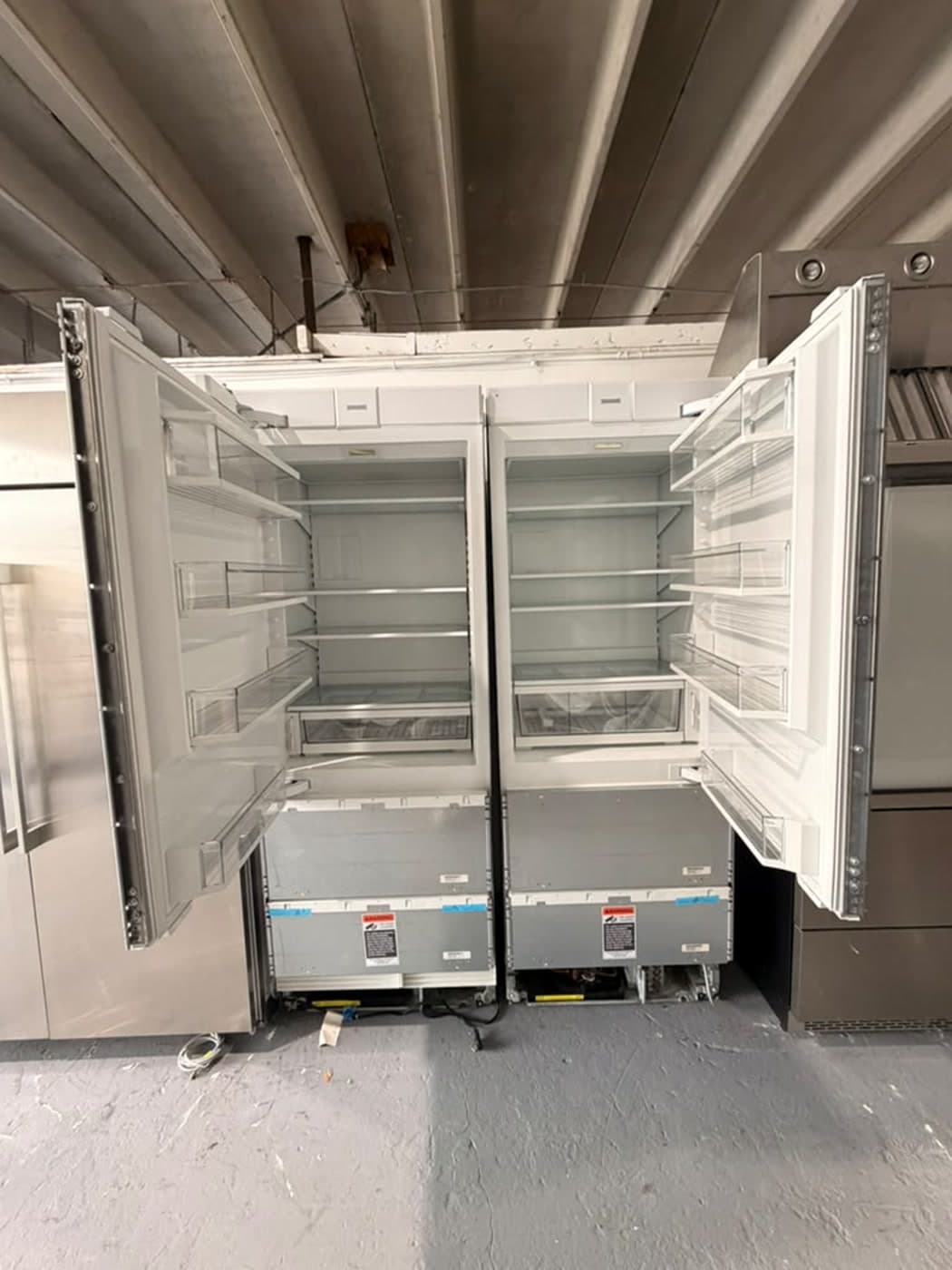 Actual sub-zero panel-ready bottom-freezer pair photographed in Oakland Park — actual units · refrigerator doors open